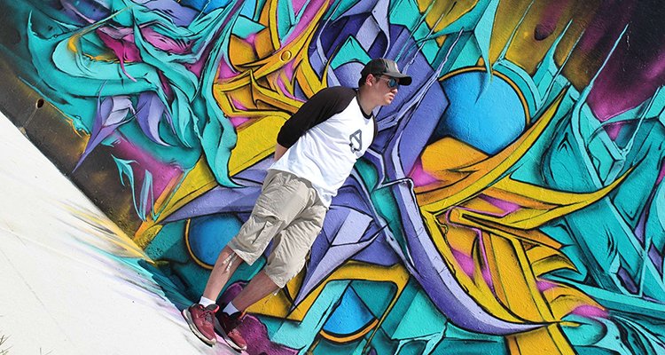 Man stands before colorful graffiti wall