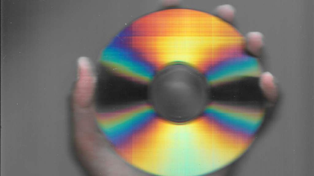 Hand holds compact disc, rainbow effect