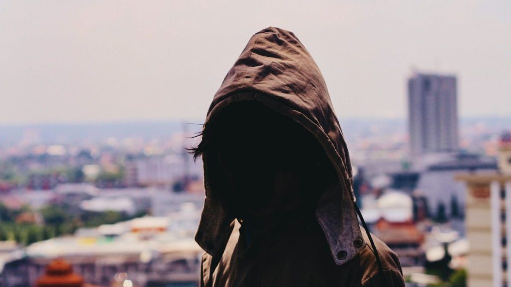 Hooded figure standing alone outside